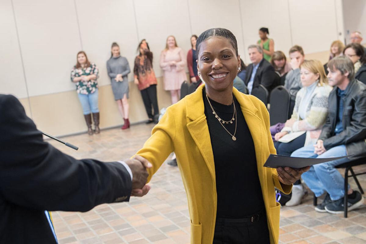 A student shakes a faculty member’s hand during an event.