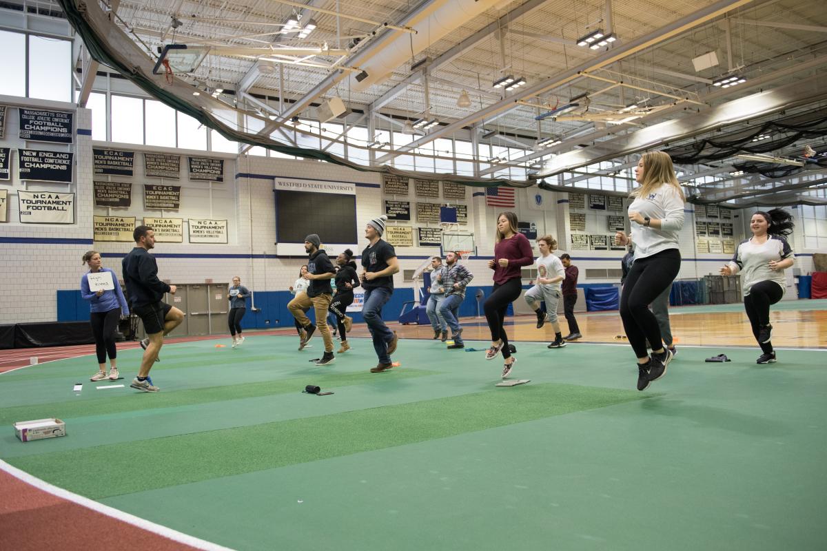 Group of students jumping off a green gymnasium floor