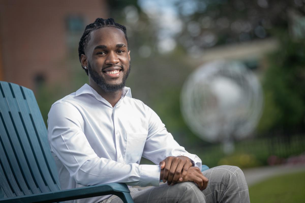 Student seated outside of campus globe smiling.