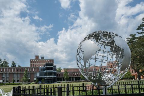 The globe sculpture on the campus green with the Ely Campus Center in the background