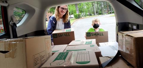 Photo of volunteers taking boxes of donations out of a car