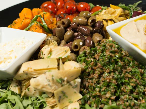 Olive bar spread including cheese, tabouli, olive oil, and tomatoes.