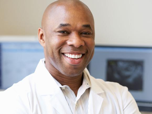 Online career training student smiling with a computer behind him.