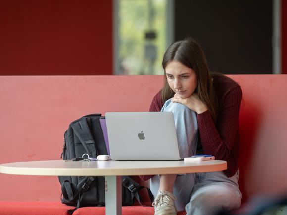 Student studying with a laptop and backpack.