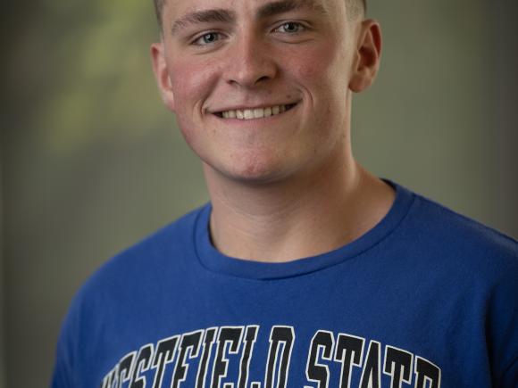 Matt Crusha ’27 smiles for a portrait while wearing a blue Westfield State University T-shirt.
