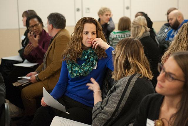 A small classroom of diverse students engage in discussions.