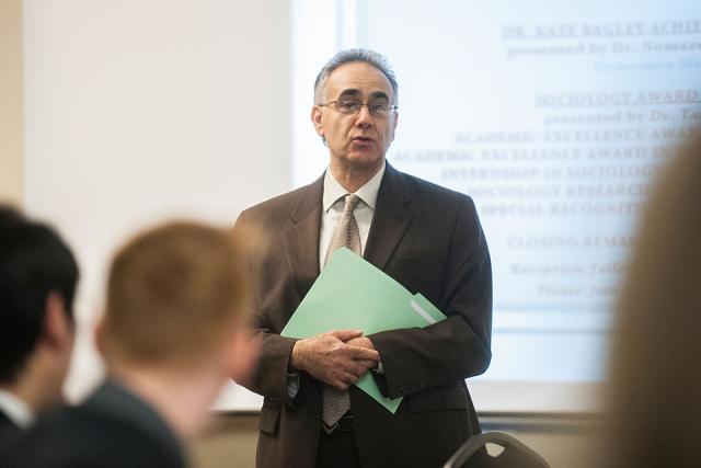 A professor gives a lecture at the front of a classroom.