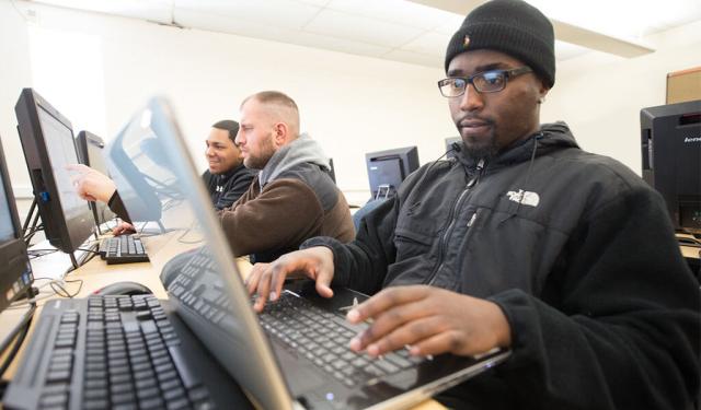 Three students work in a computer lab.