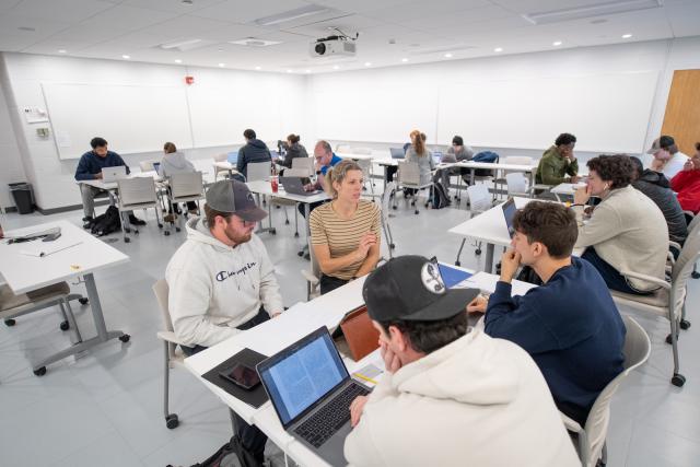 Classroom photo of students in computer lab with faculty working closely with them in small groups.