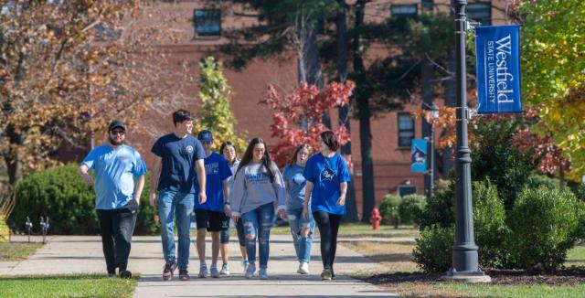 A group of seven students walk across the Westfield State University campus.