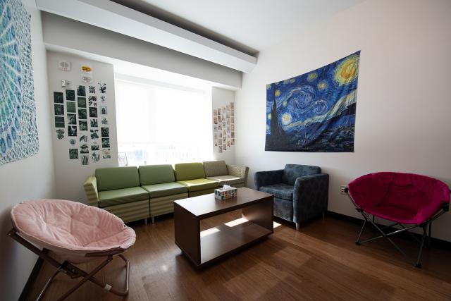 A shared living room space furnished with multiple chairs, a small couch, and a coffee table.