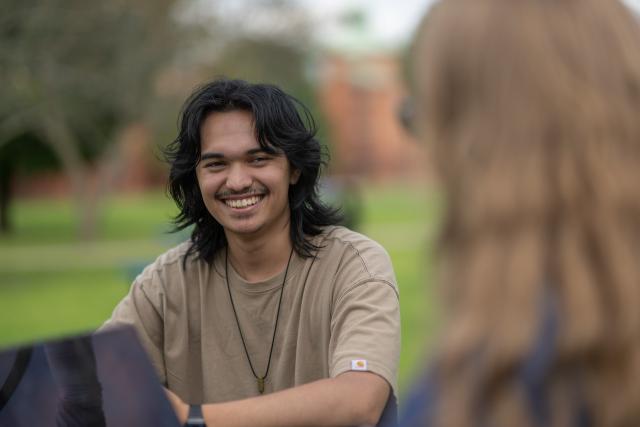 Communication student smiling with laptop.