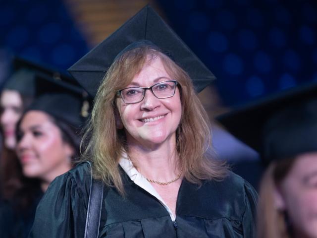 MPA student smiling at commencement wearing a cap and gown.