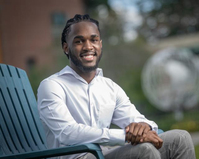 Student seated outside of campus globe smiling.