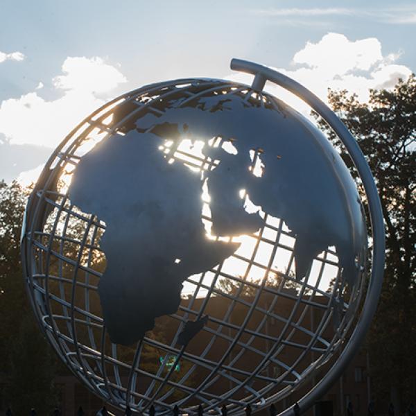 Sunlight shines through the globe sculpture on the campus green