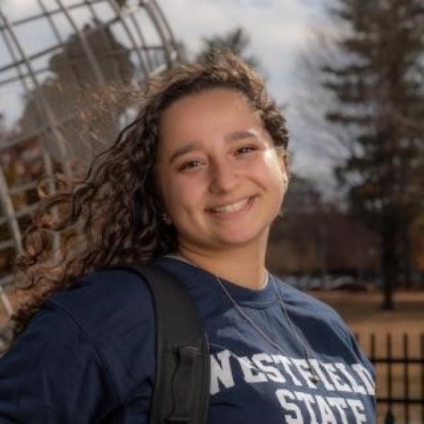 Student smiling wearing a WSU shirt at the campus globe.