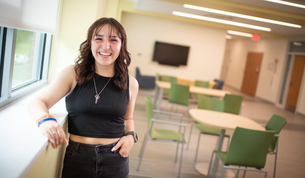 TRIO student wearing black pants and shirt with brown shoulder length hair smiling.