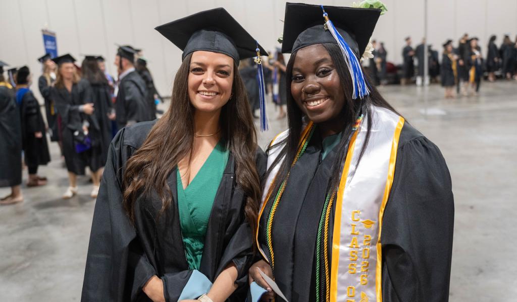 Two graduate students at commencement.