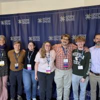 Dr. Christine von Renesse, Dr. Arne Christenson, Aiden Robert ’24, Jessica Peitzsch ’24, Kyle Morandi ’24, and Maddie Boyer ’24 at the 2024 NOYCE conference in Cambridge, MA. They pose together in front of a blue banner.